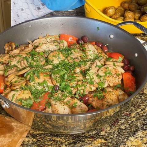 An image of chicken marengo cooked inside of an electric skillet. The chicken marengo is topped with parsley. The dish contains chicken, tomatoes, and olives.