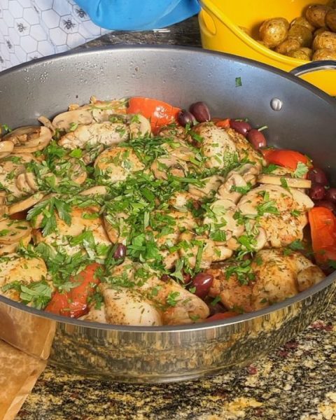 An image of chicken marengo cooked inside of an electric skillet. The chicken marengo is topped with parsley. The dish contains chicken, tomatoes, and olives.